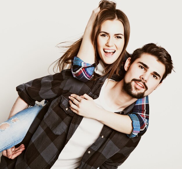 Emotional, life style, happiness and people concept: Happy loving couple. Young man piggybacking his girlfriend. Studio shot over white background.Special Fashionable toning photos.
