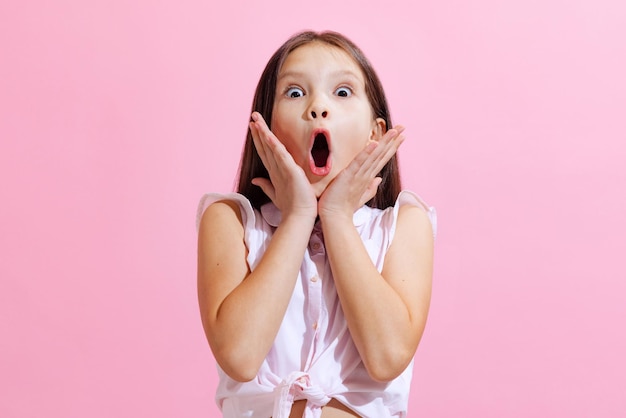 Emotional little charming girl kid wearing blouse isolated on pink background concept of children