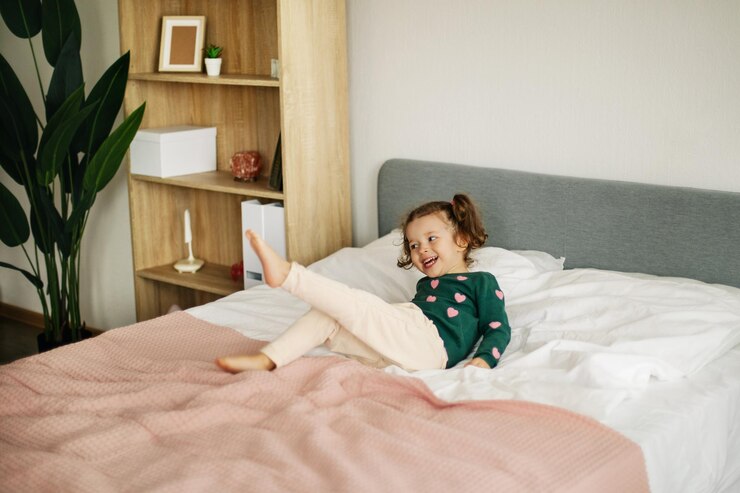 Photo an emotional little girl is playing on the bed in the bedroom and laughing