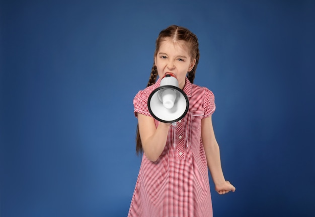 Emotional little girl shouting into megaphone on color