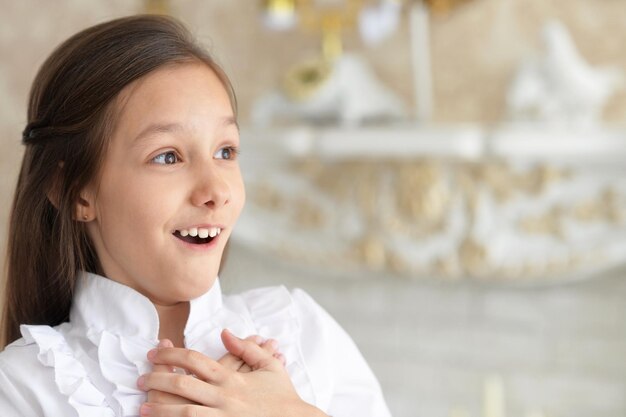 Emotional little girl in white blouse posing at home