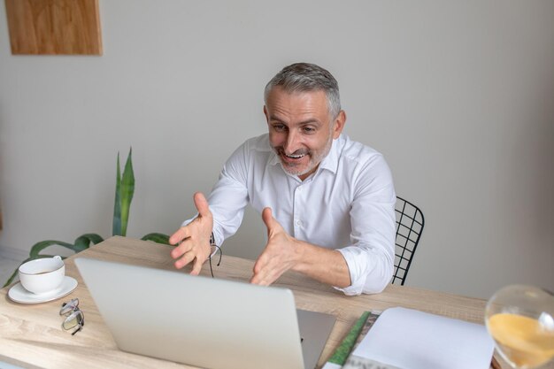 Emotional man talking on video call sitting at table