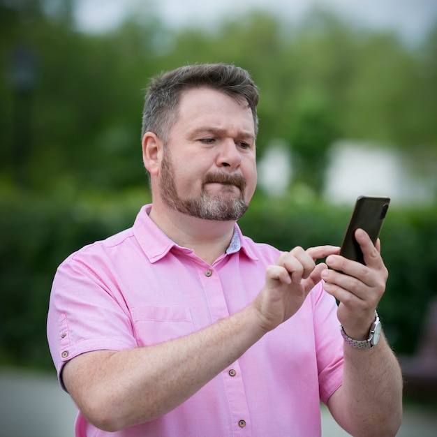 Emotional man uses a smartphone on the street. Communication in social networks of the Internet