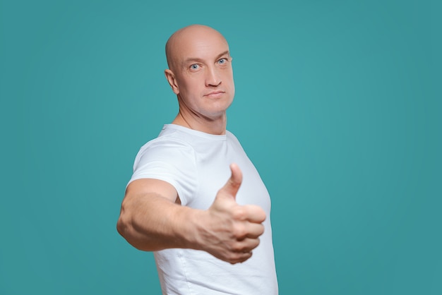 An emotional man in a white t-shirt shows with a hand gesture that everything is cool