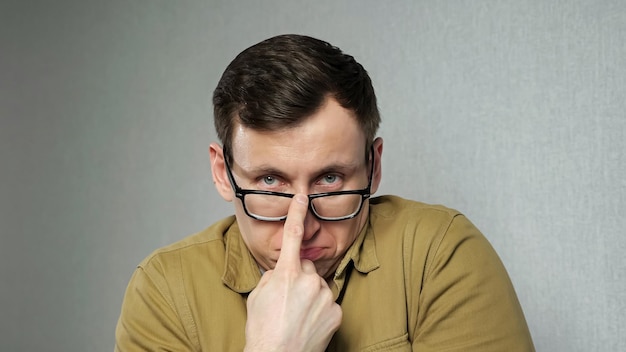 Emotional man with bad eyesight adjusts blackrimmed glasses