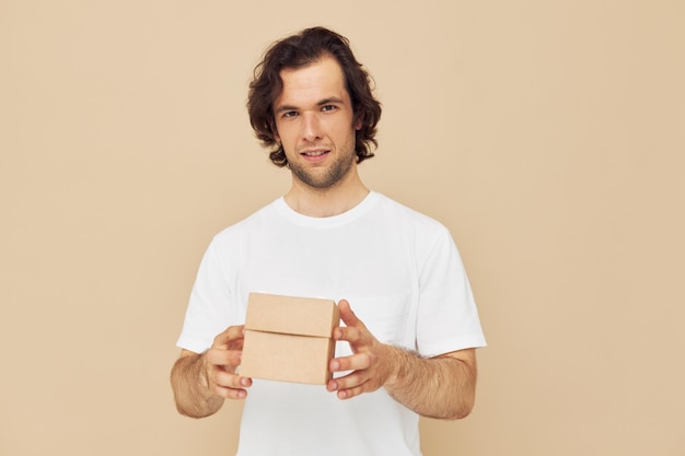 Emotional man with gift small box on beige background