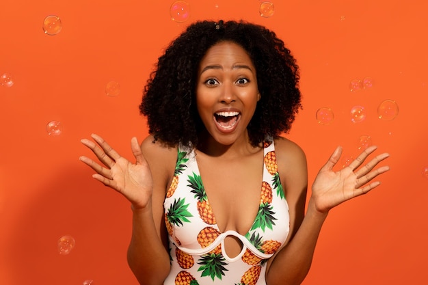 Photo emotional millennial african woman among water bubbles orange background