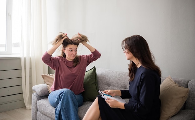 感情的な患者が灰色のソファに座って、女性の心理学者と話している。専門医療