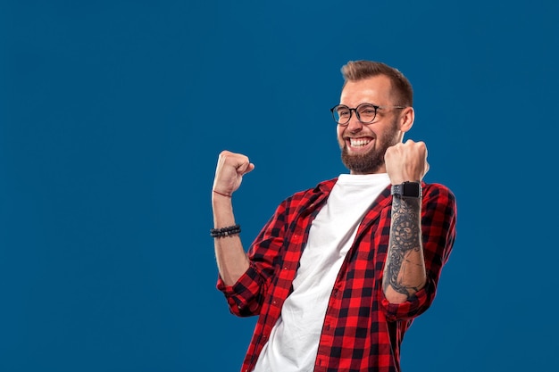 Emotivo e concetto di persone giovane uomo barbuto in camicia a scacchi stile hipster vincitore