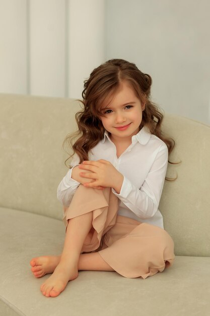 Emotional portrait of a beautiful girl in a white shirt on a beige background