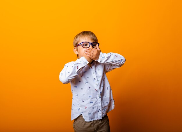 Emotional portrait of a boy with glasses. A surprised child looks at the camera.