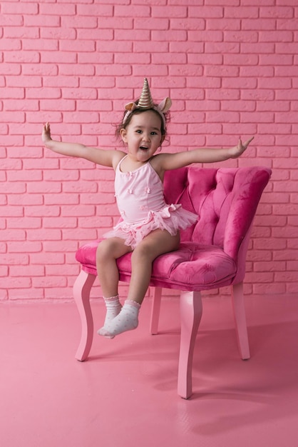 emotional portrait of little asian girl in a ballerina costume costumes on pink background