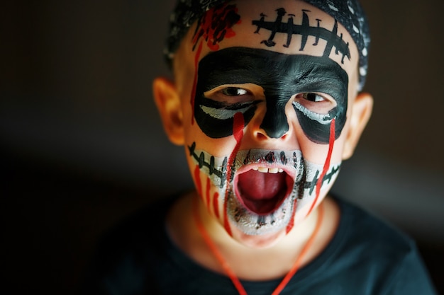 Emotional portrait of a screaming boy with a scary zombie on his face