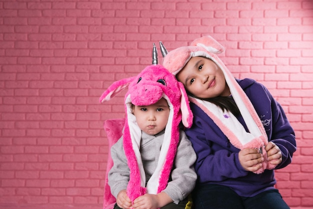 Ritratto emotivo di due ragazze asiatiche in costumi di halloween su sfondo rosa