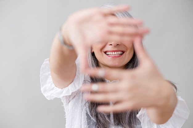 Emotional portraits of a paled long hair asian matured woman on grey wall