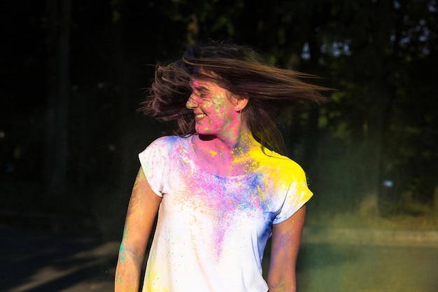 Emotional pretty woman with hair in motion having fun with Holi paint