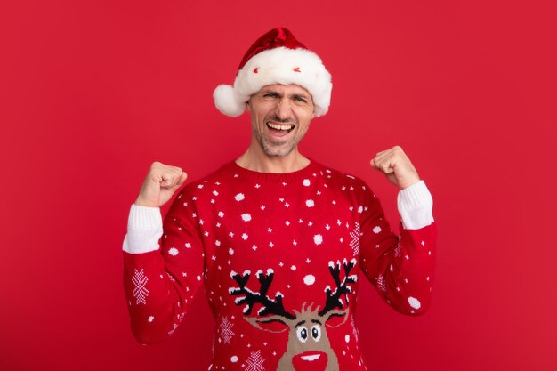 Emotional santa man in holiday sweater and santa hat on studio background christmas sale or special winter offer