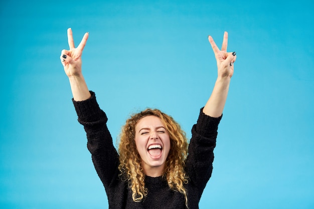 Foto emotional soddisfatto giovane attraente attraente zenzero riccio con la bocca aperta festeggia e incoraggia un successo alzando le mani