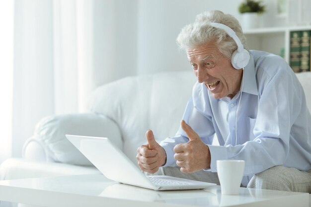 Emotional senior man using laptop at home