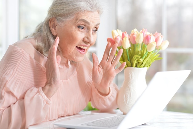 Emotional senior woman with laptop