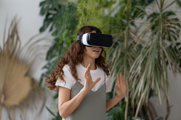 Emotional shocked woman in vr helmet using interactive technology for the first time at home garden