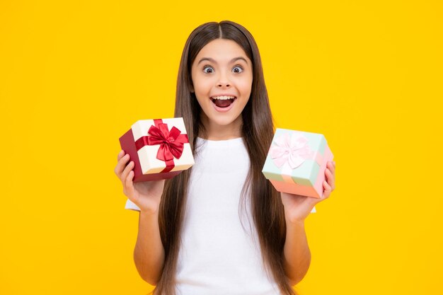 Emotional teenager child hold gift on birthday Funny kid girl holding gift boxes celebrating happy New Year or Christmas Excited teenager glad amazed and overjoyed emotions