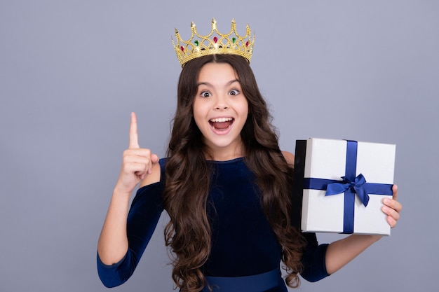 Emotional teenager princess in crown child hold gift on\
birthday funny kid girl holding gift boxes