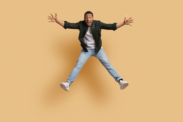 Эмоционально взволнованный молодой африканский парень прыгает в воздух