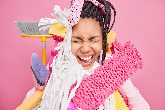 Emotional woma screams loudly uses different cleaning tools