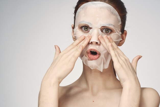 Emotional woman cosmetic face mask closeup light background