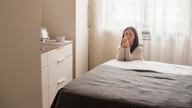 Emotional woman saying a prayer at home