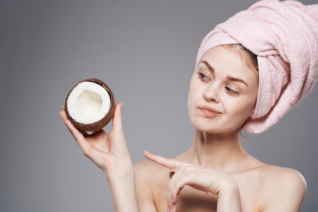 Emotional woman with a pink towel on her head coconut in the hands of tropical fruits clean skin