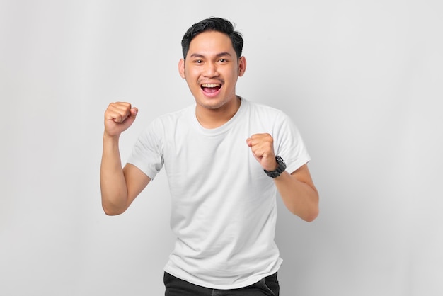 Emotional young Asian man celebrating big success isolated on white background