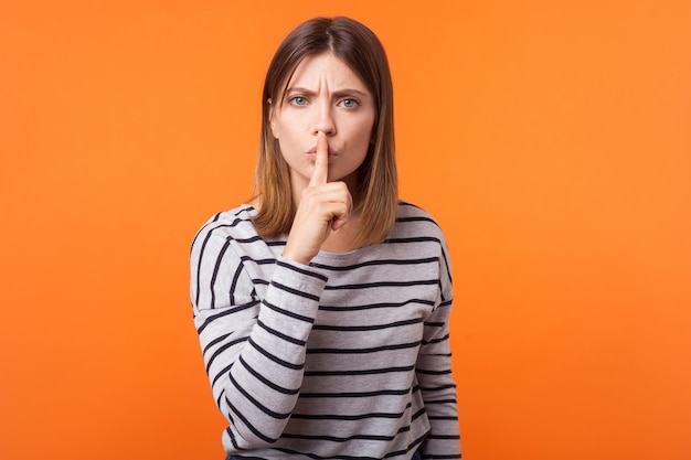 Emotional young brunette woman on orange background