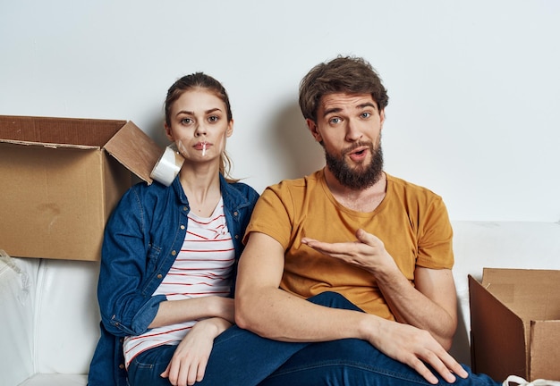Emotional young couple on the couch with cardboard boxes interior High quality photo