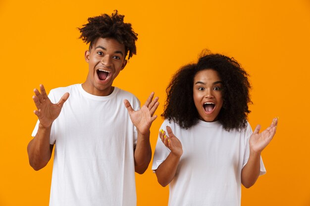 Emotional young cute african couple posing isolated over yellow space.