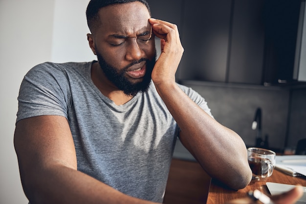 Emotional young man making face from sharp pain