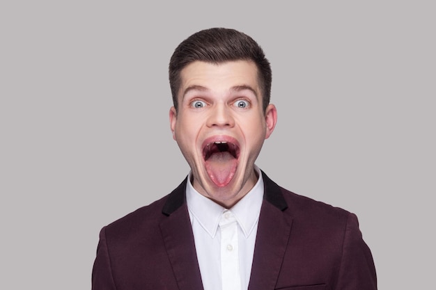 Emotional young man in suit on gray background