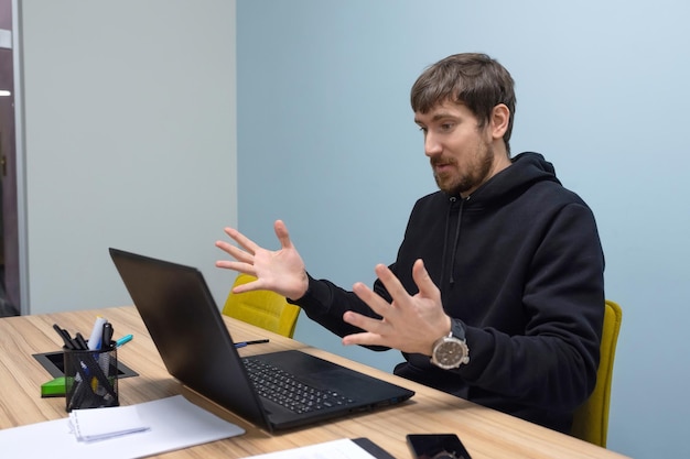 Emotional young man working in the office on a laptop