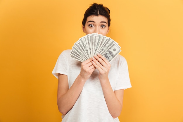 Emotional young pretty woman holding money covering face