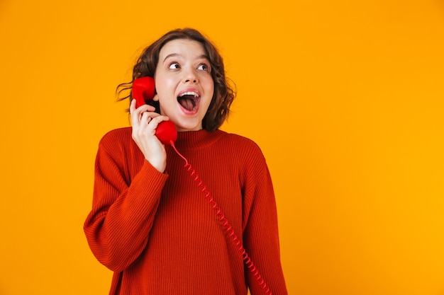 emotional young pretty woman posing isolated on yellow wall talking by telephone.