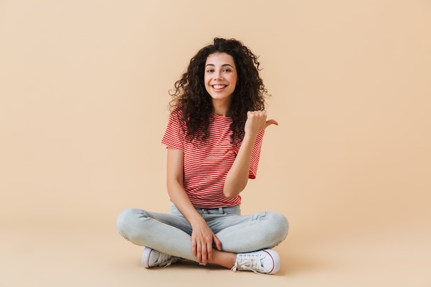 Emotional young woman isolated over beige wall