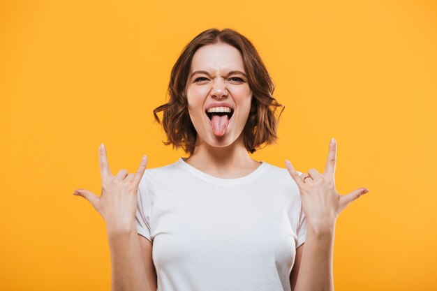 Emotional young woman showing rock gesture looking camera