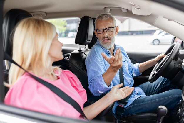 Foto emotioneel gepensioneerd echtpaar dat ruzie maakt en tegen elkaar schreeuwt in de auto