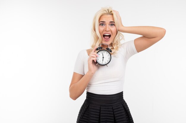 Emotioneel meisje in een wit t-shirt houdt een klok met kopie ruimte