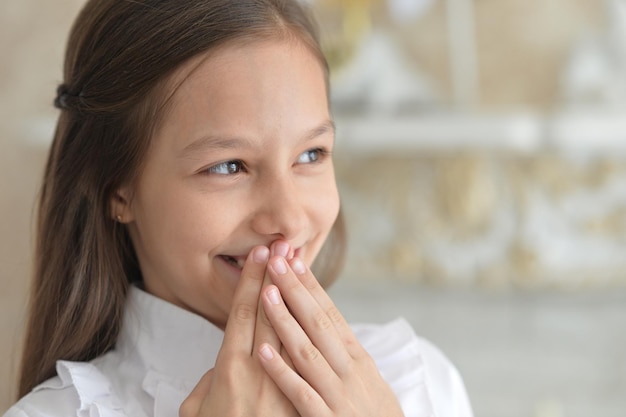 Emotioneel meisje in witte blouse die thuis poseert