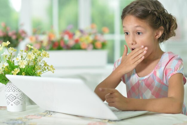 Emotioneel verrast schattig meisje met laptop thuis