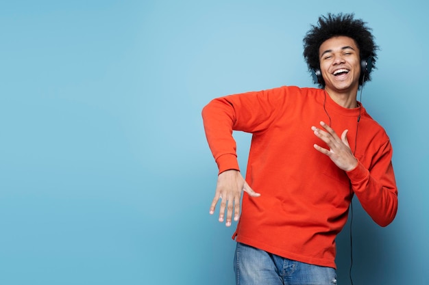 Emotionele Afro-Amerikaanse man met koptelefoon die muziek luistert, geïsoleerd danst, kopieer ruimte