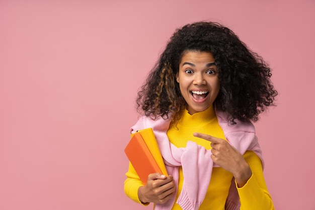 Emotionele afro-amerikaanse student met boeken wijzende vinger op kopieerruimte