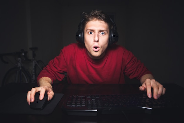 emotionele gamer met een verbaasd gezicht om thuis te zitten op de computer